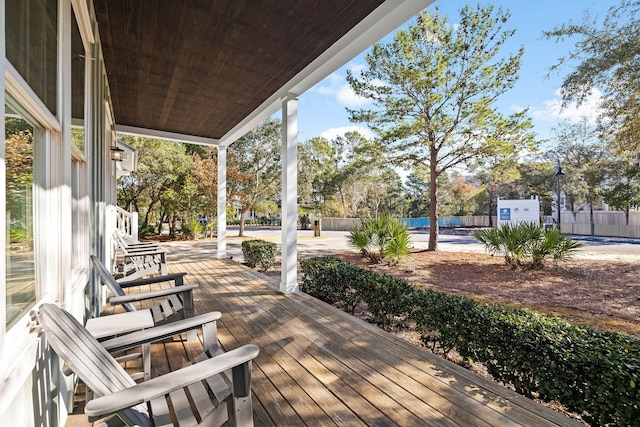 wooden deck featuring a porch and a storage unit