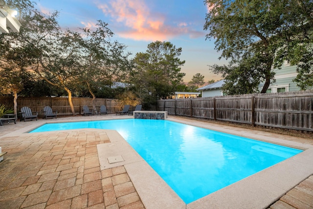 pool at dusk featuring a patio