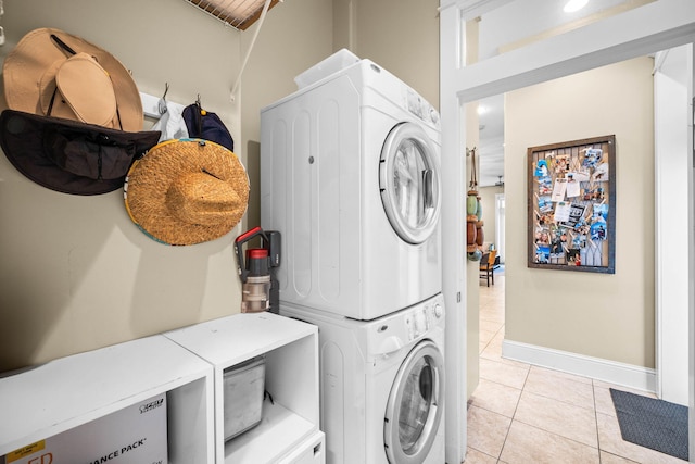 laundry area with light tile patterned floors and stacked washing maching and dryer