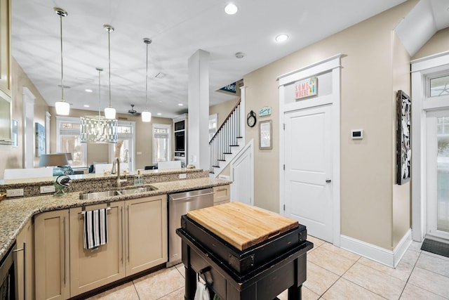 kitchen featuring sink, light stone countertops, light tile patterned flooring, decorative light fixtures, and stainless steel dishwasher