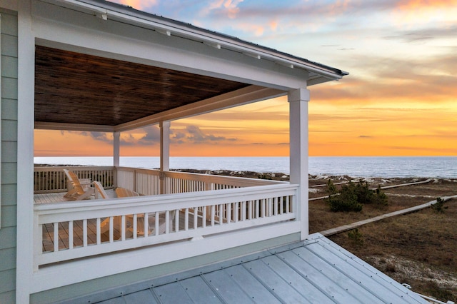 deck at dusk featuring a water view