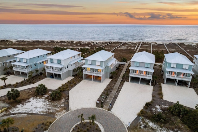 aerial view at dusk with a water view and a view of the beach