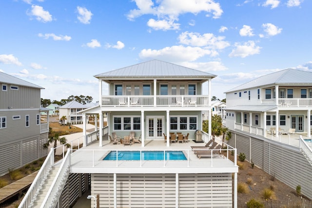 rear view of property with french doors, a balcony, a fenced in pool, and a patio area