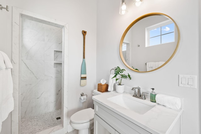 bathroom with vanity, a tile shower, and toilet