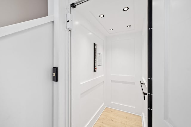 hallway featuring elevator and light hardwood / wood-style floors