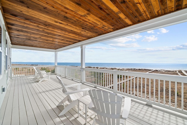 wooden terrace featuring a water view and a beach view