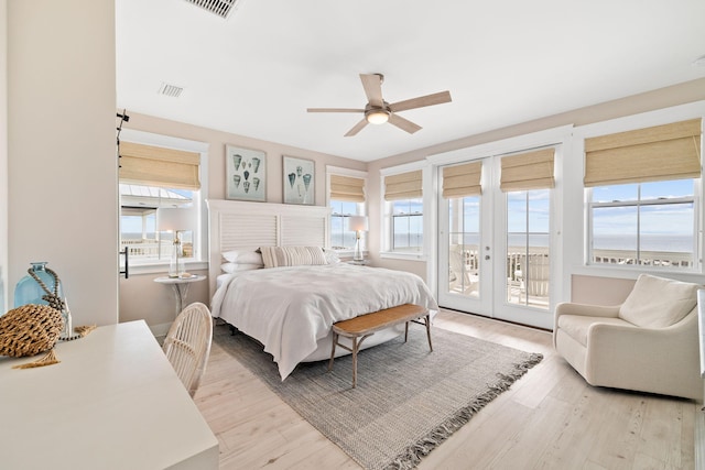 bedroom with multiple windows, access to exterior, light wood-type flooring, and french doors