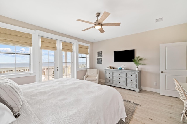 bedroom featuring ceiling fan, access to exterior, a water view, french doors, and light wood-type flooring