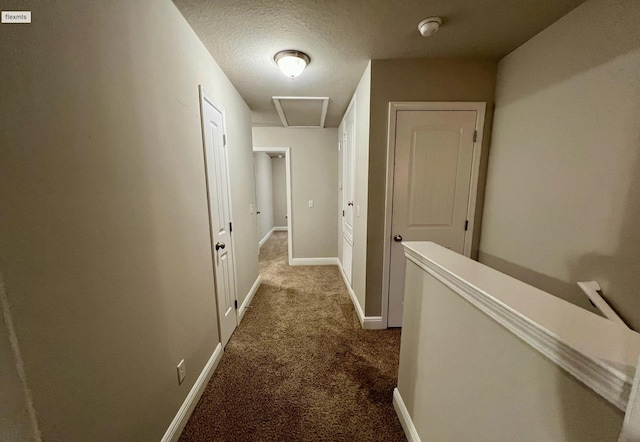 corridor with a textured ceiling and dark colored carpet