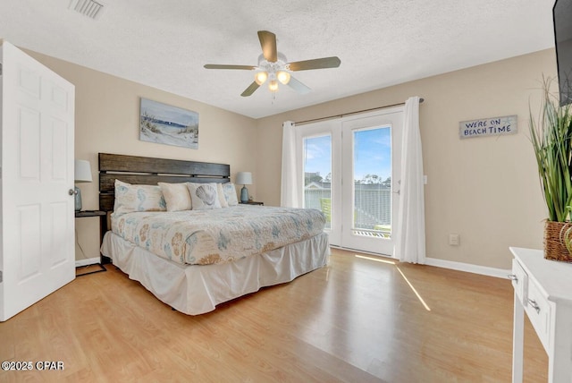 bedroom with hardwood / wood-style flooring, access to outside, and a textured ceiling