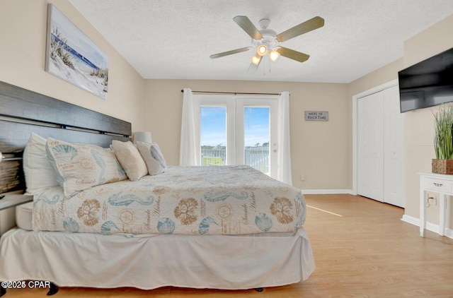 bedroom with ceiling fan, access to outside, a textured ceiling, and light hardwood / wood-style flooring