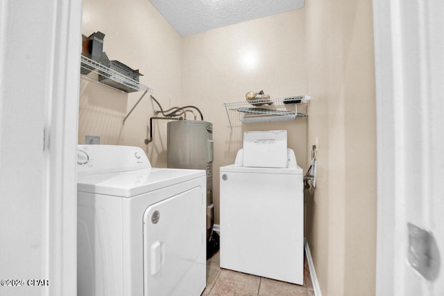 washroom featuring light tile patterned floors, washing machine and dryer, water heater, and a textured ceiling