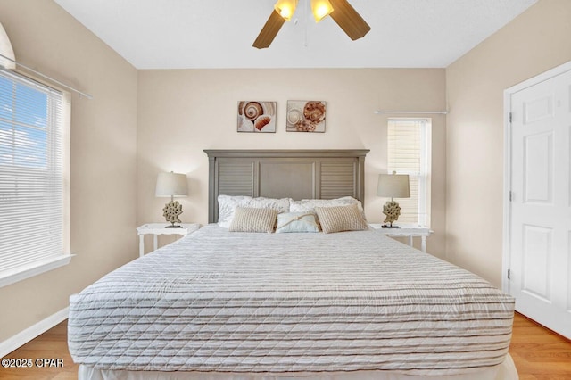 bedroom featuring ceiling fan, multiple windows, and light hardwood / wood-style flooring