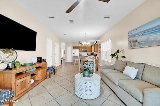 living room featuring light tile patterned floors, ceiling fan with notable chandelier, and a textured ceiling