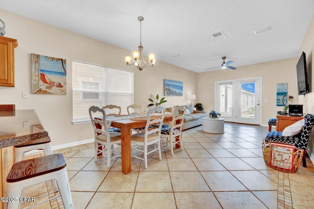 tiled dining space featuring ceiling fan with notable chandelier and a textured ceiling