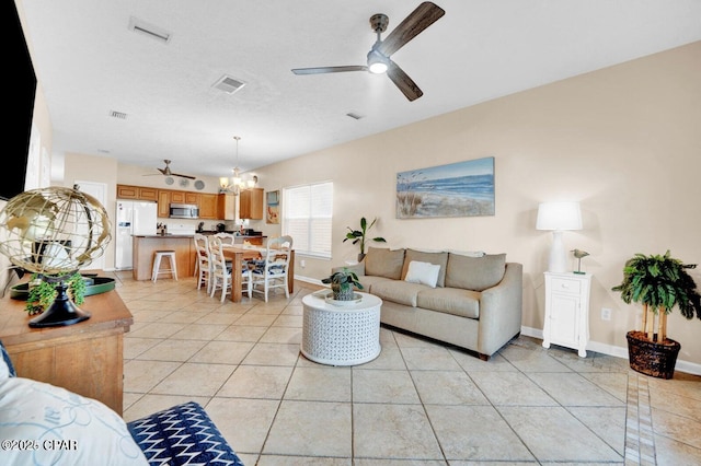 living room with ceiling fan with notable chandelier, light tile patterned floors, and a textured ceiling