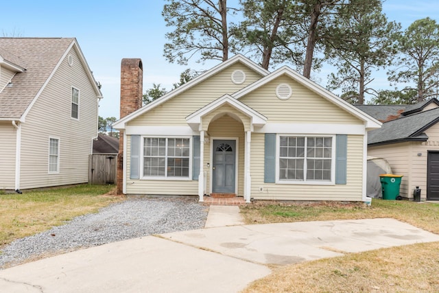 bungalow-style home featuring fence, a chimney, and a front lawn