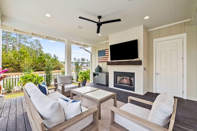 wooden deck with ceiling fan and an outdoor living space with a fireplace