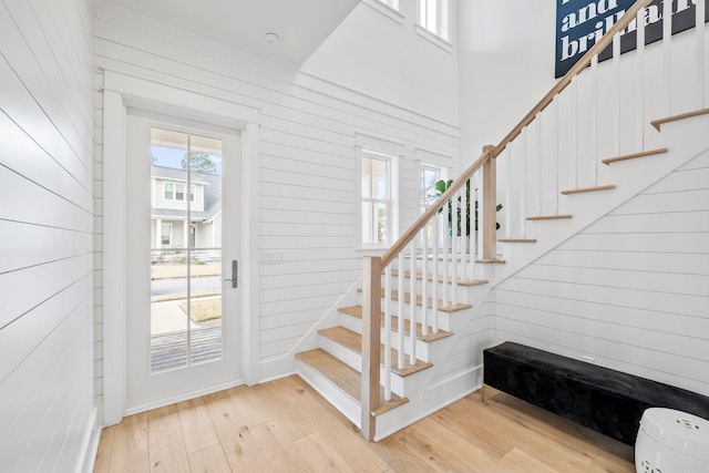 stairs featuring a towering ceiling, wood-type flooring, and wooden walls