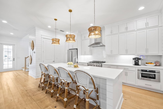 kitchen with pendant lighting, appliances with stainless steel finishes, a center island with sink, and white cabinets