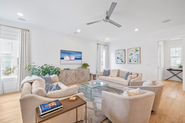 living room with ornamental molding, ceiling fan, and light wood-type flooring