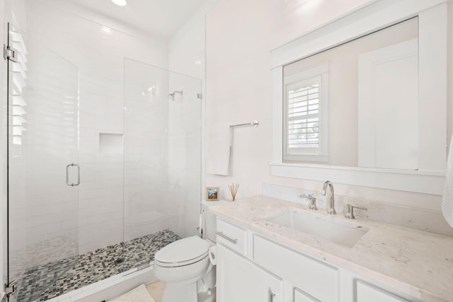 bathroom featuring vanity, a shower with door, and toilet