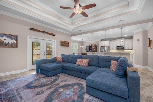 living room featuring french doors, ornamental molding, a raised ceiling, and a wealth of natural light