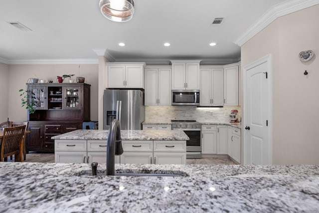 kitchen featuring sink, crown molding, stainless steel appliances, light stone countertops, and white cabinets