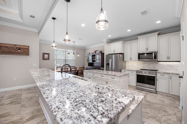 kitchen with appliances with stainless steel finishes, decorative light fixtures, sink, and a spacious island