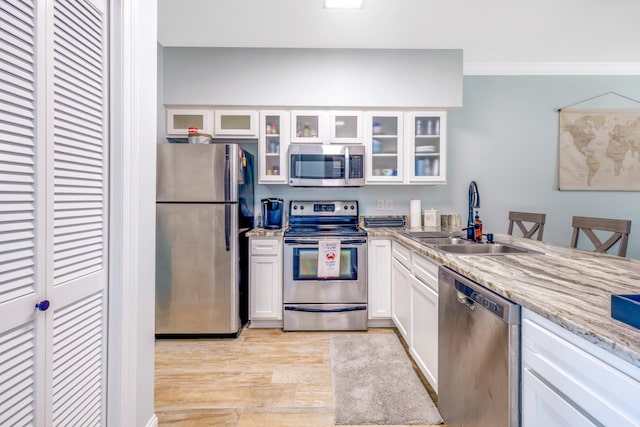 kitchen with sink, white cabinets, stainless steel appliances, crown molding, and light hardwood / wood-style flooring