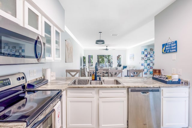 kitchen featuring appliances with stainless steel finishes, white cabinetry, sink, ceiling fan, and light stone countertops