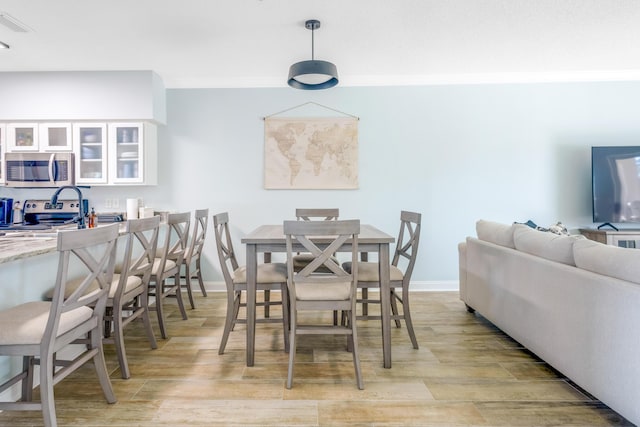 dining space with crown molding and light hardwood / wood-style flooring