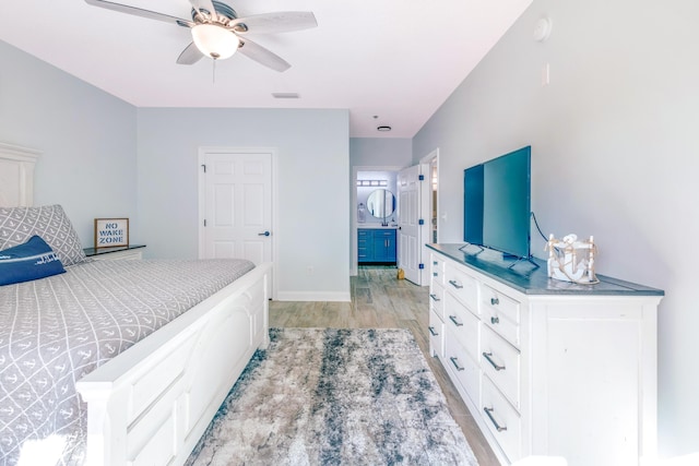 bedroom featuring ceiling fan, ensuite bath, and light hardwood / wood-style floors