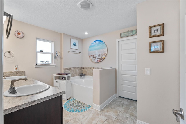 1911 Ladybird Ln, Gulf Breeze, FL 32563 - bathroom featuring double vanity, a textured ceiling, a sink, and a garden tub