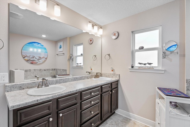 1911 Ladybird Ln, Gulf Breeze, FL 32563 - bathroom with baseboards, double vanity, a textured ceiling, and a sink