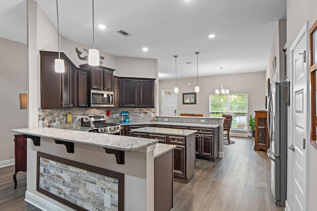 1911 Ladybird Ln, Gulf Breeze, FL 32563 - kitchen with dark brown cabinetry, a peninsula, decorative backsplash, and stainless steel appliances