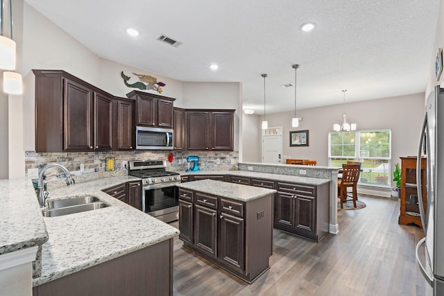1911 Ladybird Ln, Gulf Breeze, FL 32563 - kitchen with visible vents, a peninsula, appliances with stainless steel finishes, dark brown cabinetry, and a sink
