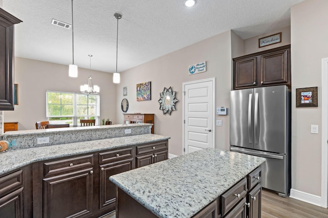 1911 Ladybird Ln, Gulf Breeze, FL 32563 - kitchen with dark brown cabinetry, a chandelier, freestanding refrigerator, a peninsula, and visible vents