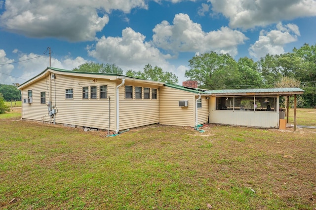 rear view of house with a sunroom and a lawn