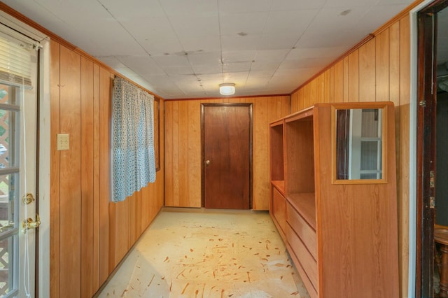 interior space with ornamental molding and wood walls