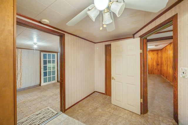 interior space with crown molding, ceiling fan, and wood walls