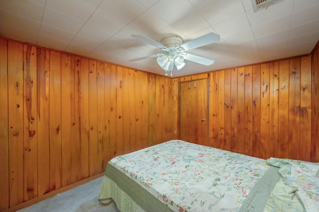 bedroom with wooden walls, light colored carpet, and ceiling fan