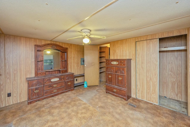 bedroom with ceiling fan, wooden walls, carpet floors, and a textured ceiling