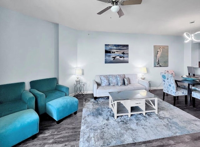 living area featuring dark wood-type flooring, baseboards, and ceiling fan with notable chandelier