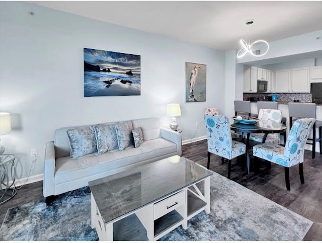 living room with an inviting chandelier, baseboards, and dark wood-type flooring