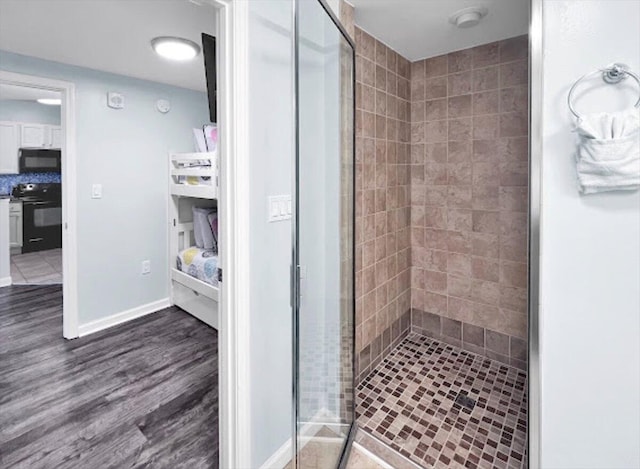 bathroom with a shower with shower door and hardwood / wood-style floors