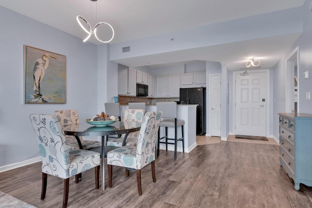 dining area with visible vents, baseboards, and wood finished floors