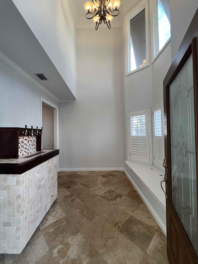 interior space featuring crown molding, plenty of natural light, a chandelier, and a high ceiling