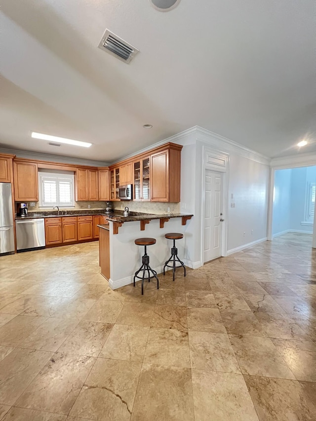 kitchen featuring crown molding, a kitchen breakfast bar, kitchen peninsula, and stainless steel appliances