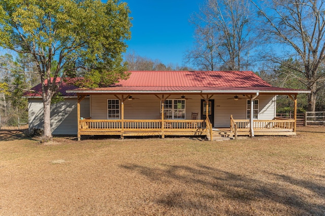 view of front of property with a wooden deck, ceiling fan, and a front yard